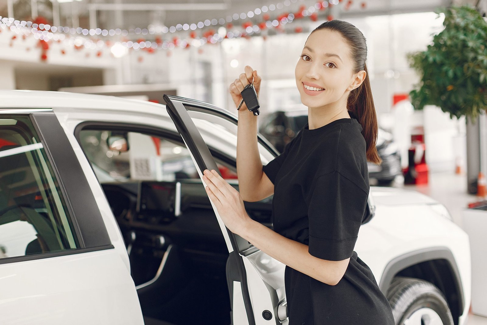 Woman in a car salon. Girl in black dress. Lady buy a car.